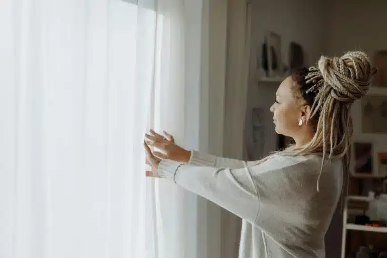Une femme qui ouvre ses rideaux